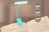 Turquoise LED reading lamp on an open book with a blurred background